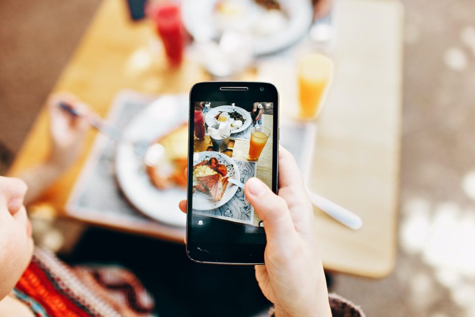 person holding phone taking picture of served food