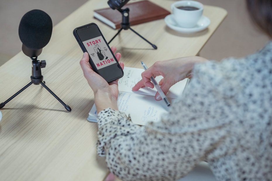 crop unrecognizable woman using smartphone at desk with microphones