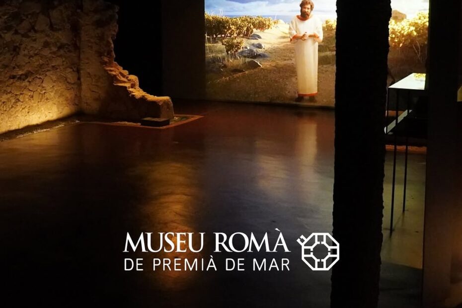 Sala del Museu Romà de Premià de Mar amb restes del jaciment il·luminades i una projecció d'un personatge romà