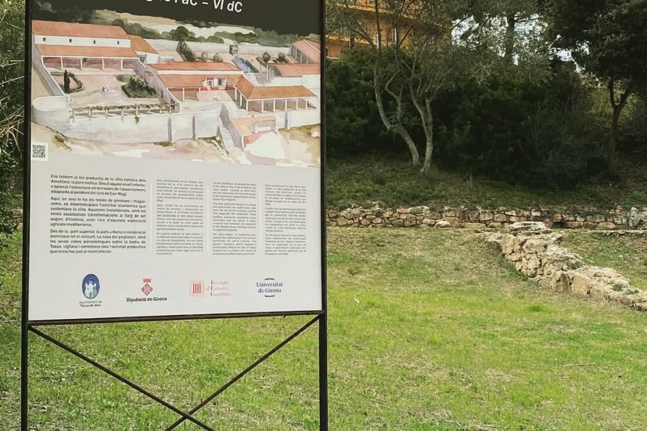 Plafó de senyalització de la Vil·la romana dels Ametllers, a Tossa de Mar, instal·lat al jaciment entre l'herba i els arbres